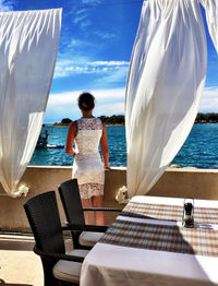 Woman standing by swimming pool in sea against sky