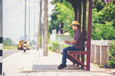 Side view of man using mobile phone while sitting outdoors