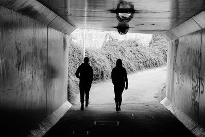 Rear view of people walking in tunnel