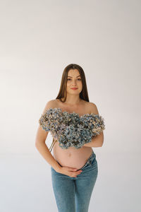 Portrait of young woman standing against white background