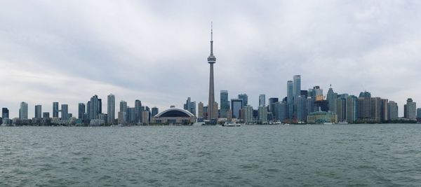 Cityscape by lake against cloudy sky