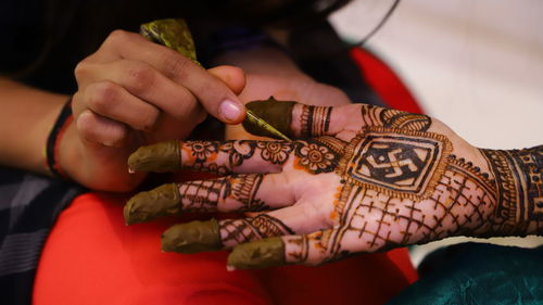 Woman making henna tattoo on hand of bride