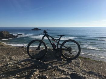 Bicycle by sea against sky