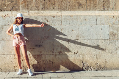 Portrait of smiling woman standing against wall