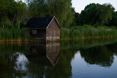 House by lake against trees