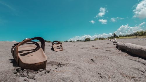 View of shoes on beach against blue sky