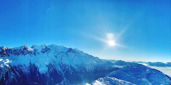 Scenic view of snowcapped mountains against blue sky