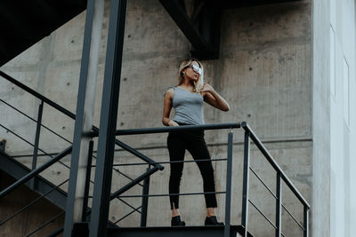 Low angle view of young woman standing on staircase