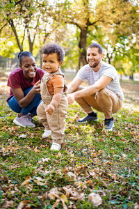 Portrait of smiling friends sitting on field