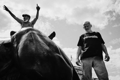 Low angle view of people riding horse against sky