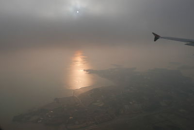 Airplane flying over sea in city against sky