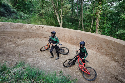 From above unrecognizable male bikers with bicycles for downhill standing in woods