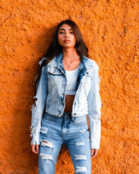 Portrait of beautiful young woman standing against wall