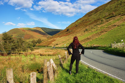 Rear view of woman standing on mountain against sky