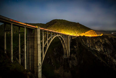 Low angle view of bridge over river against sky at night