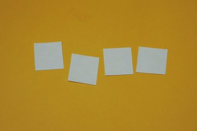 Close-up of empty sticky notes on yellow wall