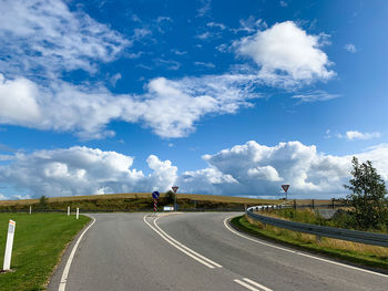 Empty road along landscape against blue sky