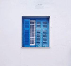 Low angle view of blue window on wall of building