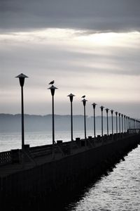 Street lights by sea against sky