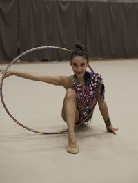 Portrait of woman dancing with plastic hoop on floor