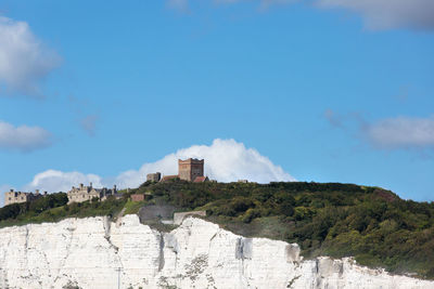 Buildings by mountain against blue sky
