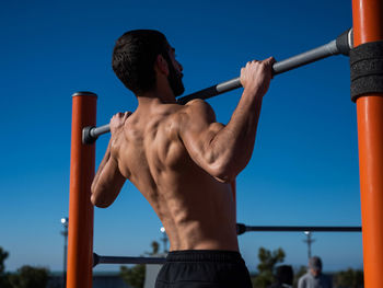 Side view of young man standing against sky