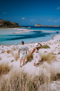 Rear view of people at beach against sky