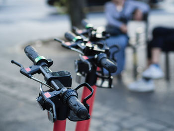 Close-up of electric push scooters parked on footpath