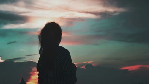 Side view of silhouette woman standing against cloudy sky during sunset