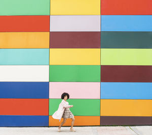 Full length of woman standing against multi colored wall