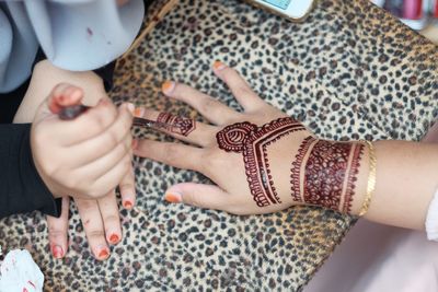 Cropped image of beautician applying henna tattoo on woman hand