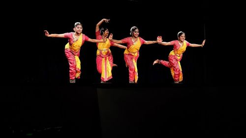 Group of people in traditional clothing against black background