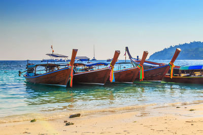 View of boats moored in sea against clear blue sky