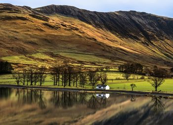Scenic view of lake and mountains against sky during sunset