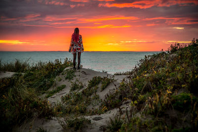 Silhouette of people standing on beach at sunset