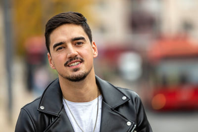 Image of handsome young man walking on the street and looking at camera.