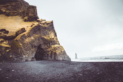 Rock formations on beach against sky