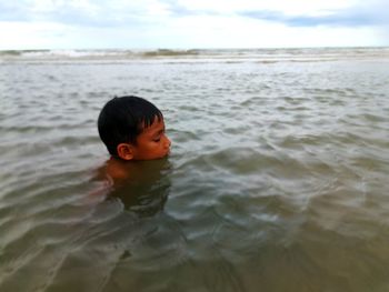 Portrait of boy in sea against sky