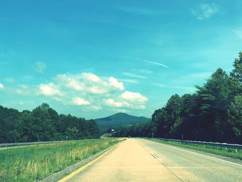 Road by trees against sky