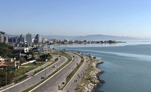 High angle view of city by sea against clear sky