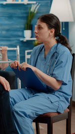 Nurse holding clipboard sitting on chair