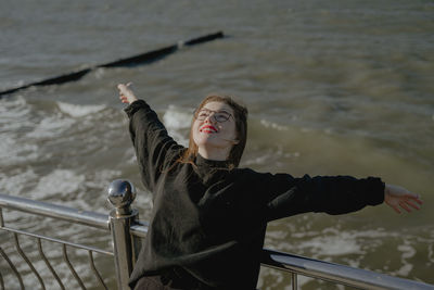 Portrait of young man with arms raised in sea