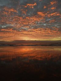 Scenic view of sea against dramatic sky during sunset