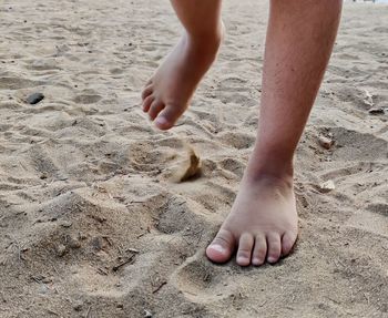 Low section of kid walking on sand at beach