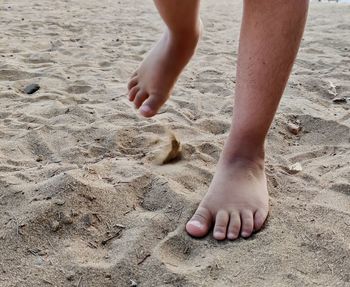 Low section of man walking on sand at beach