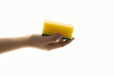 Close-up of hand holding cup against white background