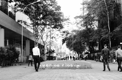 Rear view of people walking on road in city