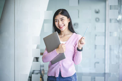 Portrait of a smiling young woman using phone
