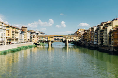 Ponte vecchio over arno river in city against sky