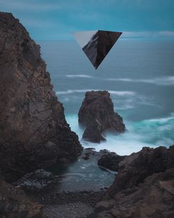 Rock formation on beach against sky